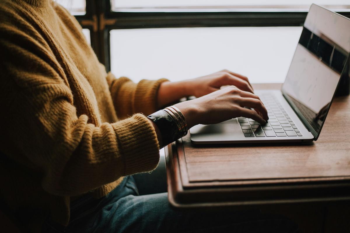 A passionate freelance writer or graphic designer working on their laptop in a cozy, creative workspace.